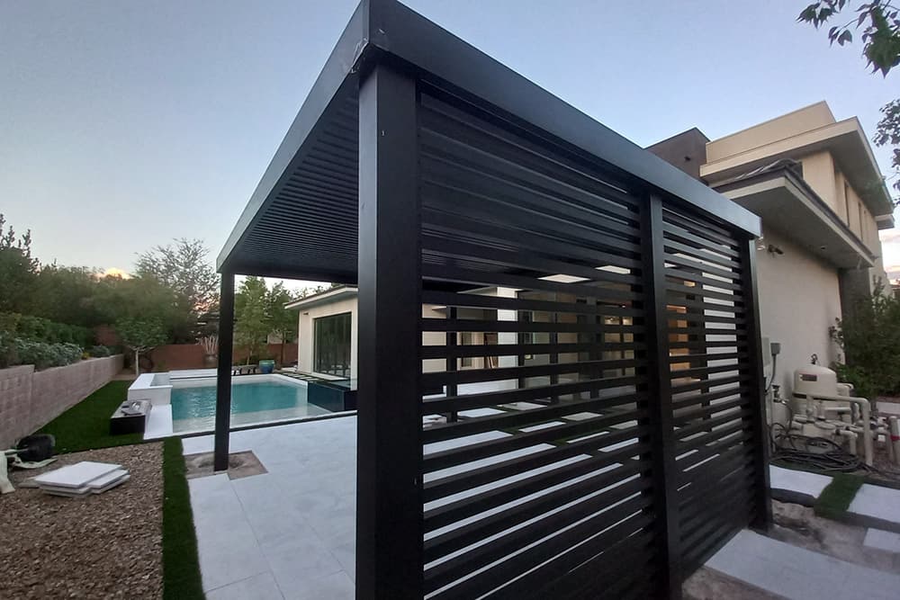 An aluminum pergola beside a home and outdoor pool