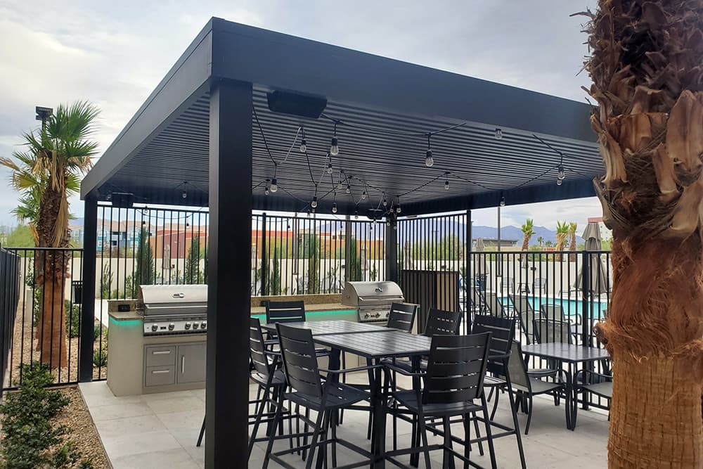 A commercial installation of a 4K patio cover with dining and outdoor cooking underneath