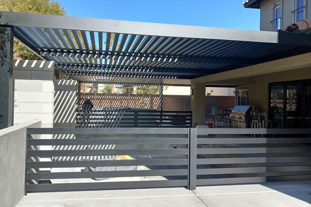 View of an outdoor kitchen and dining area with an aluminum fence and patio cover