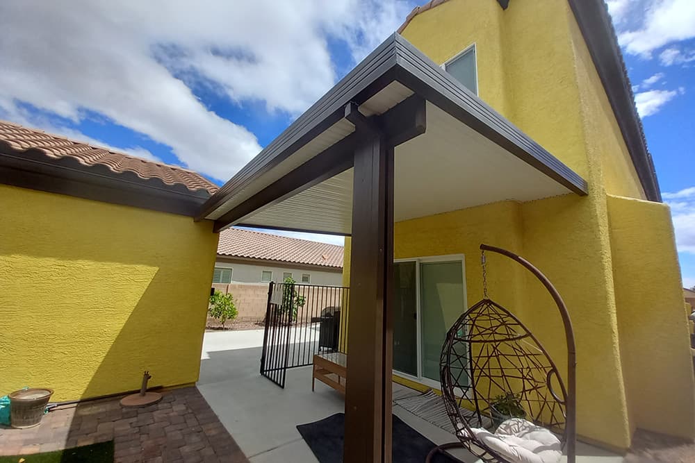 A yellow home with a solid patio cover above an entrance door